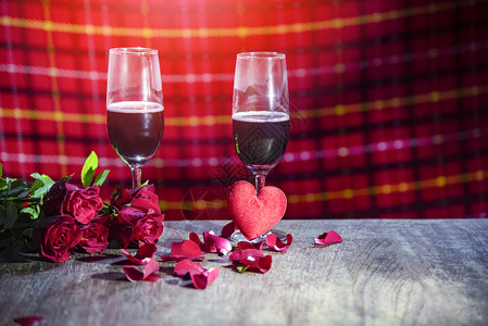 浪漫的桌子配上两对香槟玻璃红葡萄酒花瓣朵和心在生锈的餐桌上晚夜光图片