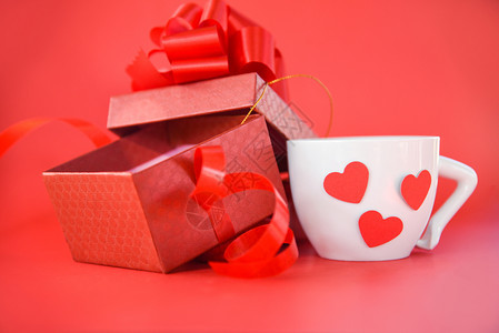 红心白咖啡杯带彩礼的盒带弓献给圣诞快乐新年红背景情人节图片
