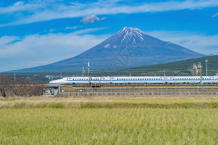 Shinkansen列车快速驾驶和通过日本东京火车站附近的藤田山配有绿稻日本图片