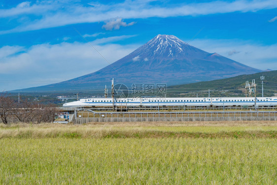 Shinkansen列车快速驾驶和通过日本东京火车站附近的藤田山配有绿稻日本图片