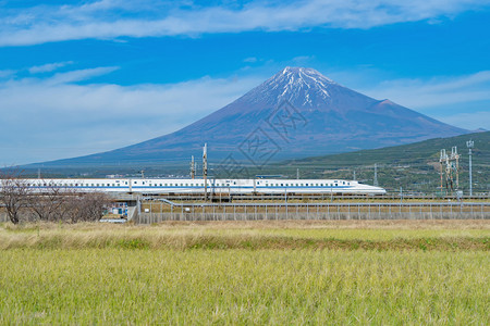 Shinkansen列车快速驾驶和通过日本东京火车站附近的藤田山配有绿稻日本图片