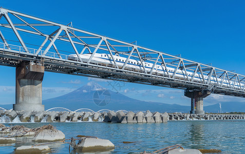 Shinkansen列车快速驾驶和经过东京火车站附近的藤田山在日本静冈富士河上架着钢桥图片