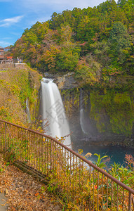 白丝瀑布秋天叶或落在山桥藤川口附近蓝天的日本多姿彩树木自然景观背图片