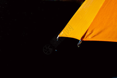 多色雨伞在滴下以黑色作为背景被隔绝图片