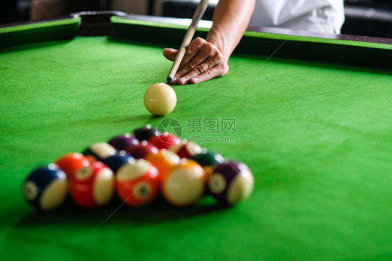 Man手和Cue臂在玩Snooker游戏或准备在绿色球桌上绿色盘上有多彩的Snooker球图片