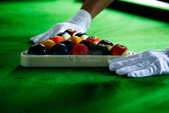 Man手和Cue臂在玩Snooker游戏或准备在绿色球桌上绿色盘上有多彩的Snooker球图片