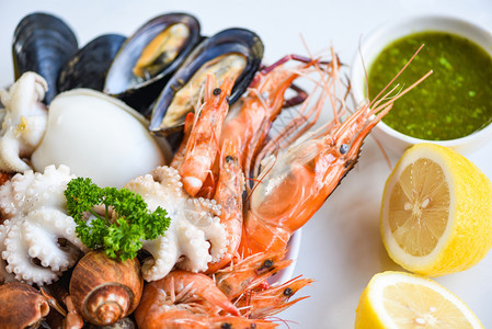 盘底白上的比伦贝壳螃蟹和海鲜酱柠檬烹饪蒸汽食品为海鲜自助餐服务的概念图片