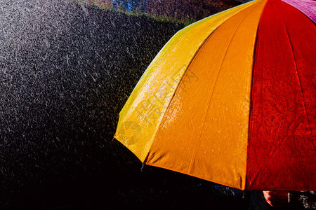 雨落在伞上太阳照射黑暗背景色图片