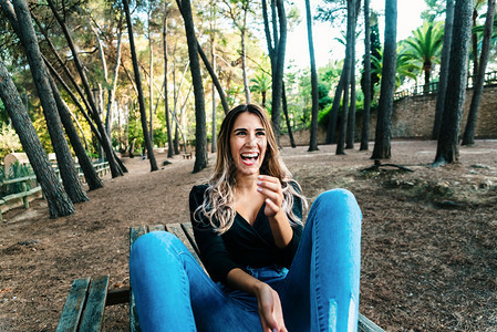笑的年轻女人坐在公园的木桌上图片