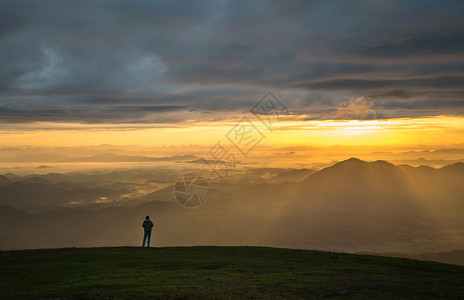 山顶上成功的男子徒山上站着日出地貌山上的人有雾黄天空山上月光照亮图片