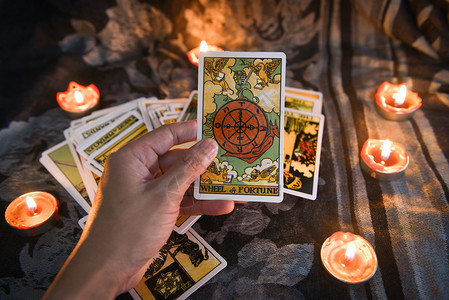 手持塔罗牌在暗幕背景上用烛光遮住塔罗牌用于占星术魔力插图精神血管镜和棕榈阅读算命员概念的黑暗背景图片