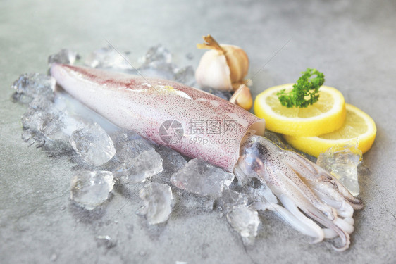 在冰上生鱿鱼有沙拉香料加柠檬大蒜有白板背景新鲜乌贼章鱼或餐饮海鲜市场煮熟食品的甲头鱼图片