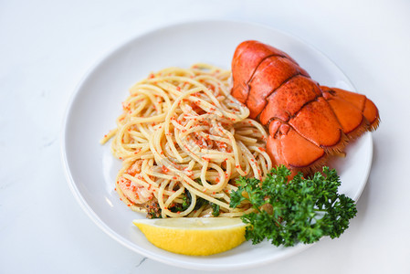 白盘子上的意大利面海鲜龙虾食品意大利面虾蛋晚饭配有香草料柠檬在餐厅桌上煮好健康的美食煮好龙虾尾图片