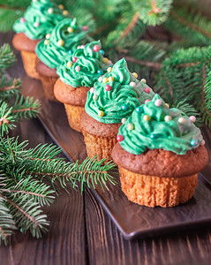 圣诞节蛋糕装饰着彩色洒满圣诞树枝的杯饼背景