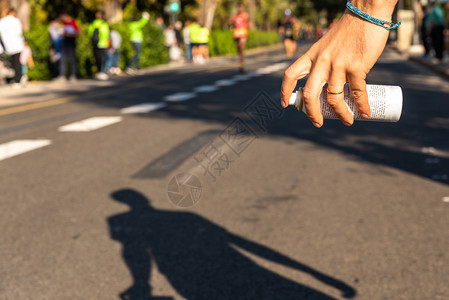 理疗师在街头跑步比赛中手握着舒缓肌肉疼痛的喷雾图片