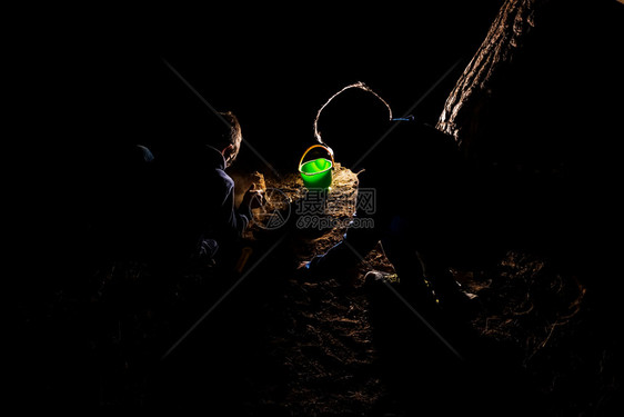 一群儿童在夜间用手电筒点燃的沙坑里玩耍图片