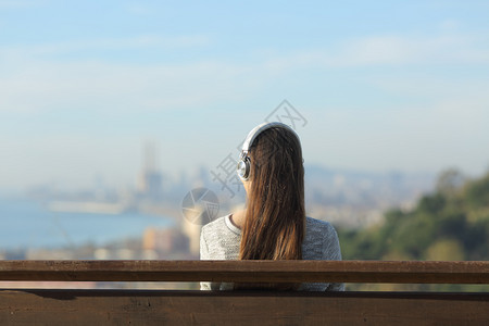 t恤 背影身戴耳机听音乐坐在市郊户外长椅上听音乐的妇女背影背景