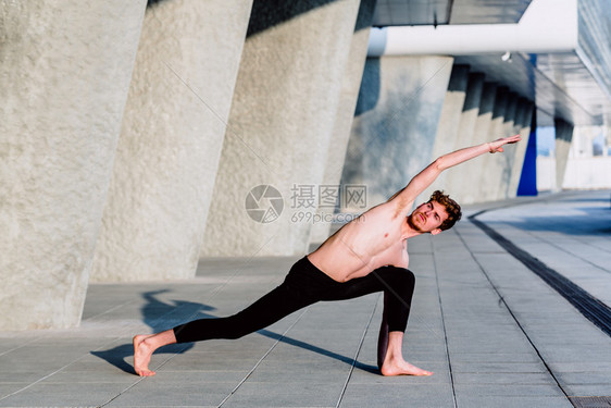 年轻男运动员在一个城市进行背部和手臂伸展练习图片