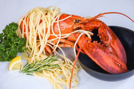 白盘上的意大利面海鲜龙虾食品配有香草料柠檬迷糖在餐厅桌上吃美食健康品煮龙虾沙拉意大利面条碗虾图片