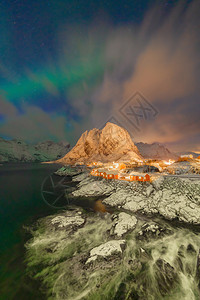 在哈姆诺伊市洛福滕岛挪威欧洲哈姆诺伊岛挪威捕鱼村有北极光和星夜间白雪山丘和树木冬季自然景观背图片