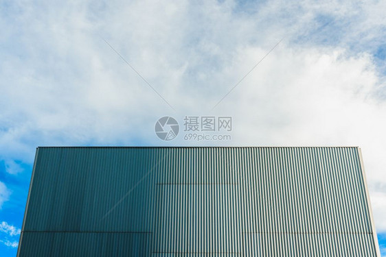 光滑的无窗建筑和蓝天空的后面铝墙图片