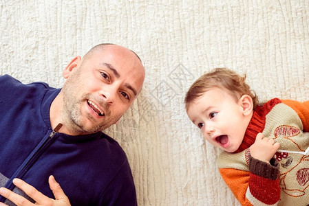 父亲和他的孩子躺在地毯上家里笑着Joaquincorbalancom图片