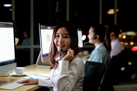 亚洲青年成人信任操作员同事团队有耳机夜间在呼叫中心工作为客户服务和技术支助使用晚夜辛勤工作24Hr7天概念图片