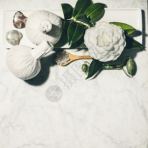 白大理石桌上的春花和各种美容产品刺花滚海盐草药按摩球基本油石块的平板成分图片