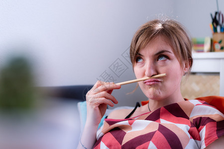 白种年轻女孩到处鬼祟的铅笔夹在鼻子和嘴唇之间图片