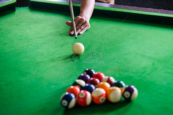 Man手和Cue臂在玩Snooker游戏或准备在绿色球桌上绿色盘上有多彩的Snooker球图片