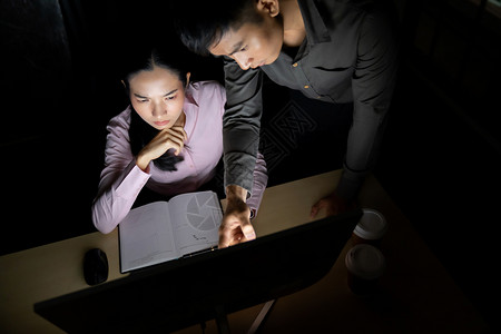 成的青亚洲商人与科莱格关于深夜在办公室工作与台式计算机的谈话背景