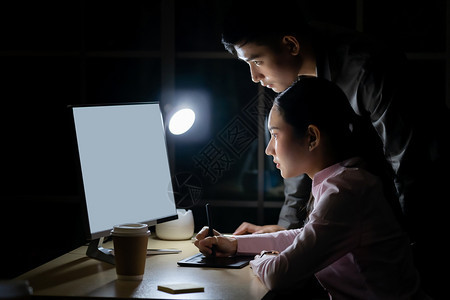 年轻成的青亚洲商人与科莱格关于深夜在办公室工作与台式计算机的谈话图片