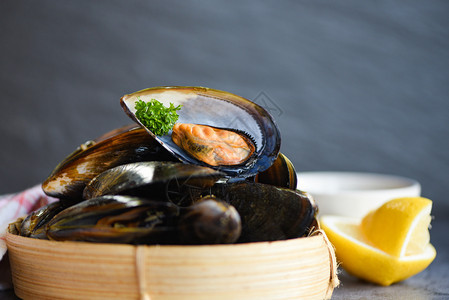餐厅的鲜海贝壳鱼竹蒸汽船上的贝壳食品竹蒸汽罐头菜食品背景上含草药柠檬的贝壳图片