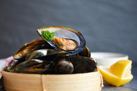 餐厅的鲜海贝壳鱼竹蒸汽船上的贝壳食品竹蒸汽罐头菜食品背景上含草药柠檬的贝壳图片