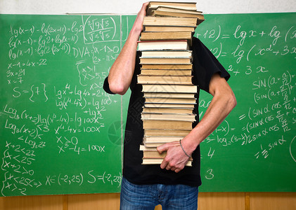 一个年轻人背着黑板拿一堆书上面有计算数学的黑板图片