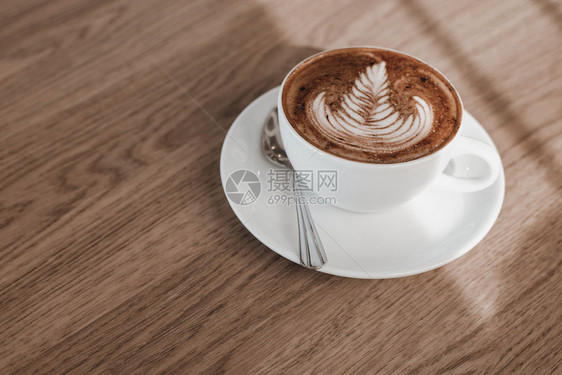 木制桌上的咖啡拿铁艺术图片