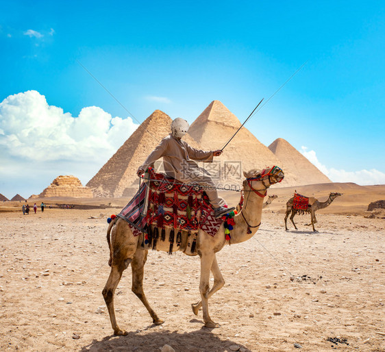 沙漠中金字塔附近骆驼上的贝都因人图片