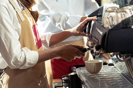 咖啡制作由现代咖啡机制造的店与在背景中工作的其他咖啡店一起制作利用小商业企家的概念背景