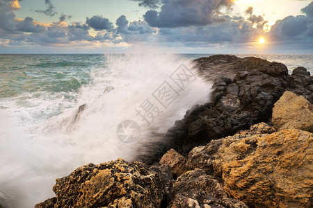 风暴的海景自然构成暴风雨期间的海浪在日落时喷洒到石头上图片