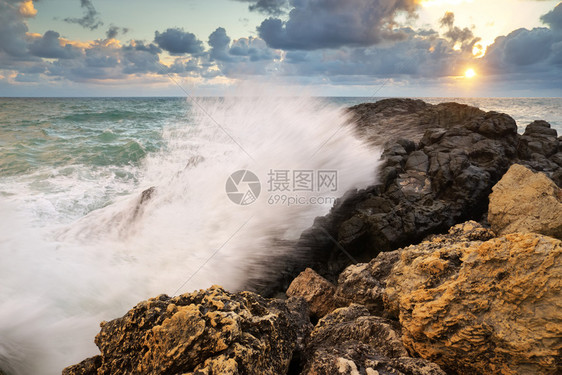 风暴的海景自然构成暴风雨期间的海浪在日落时喷洒到石头上图片