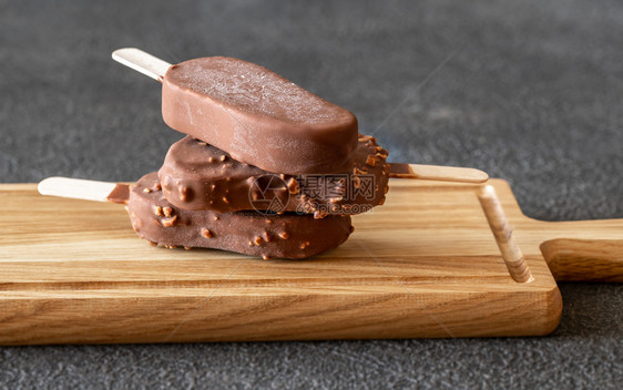 木板上巧克力覆盖的香草冰淇淋棒图片
