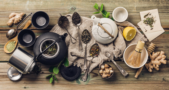 各种茶叶和壶成分干草药绿色黑茶和木制桌底的红茶平铺图片