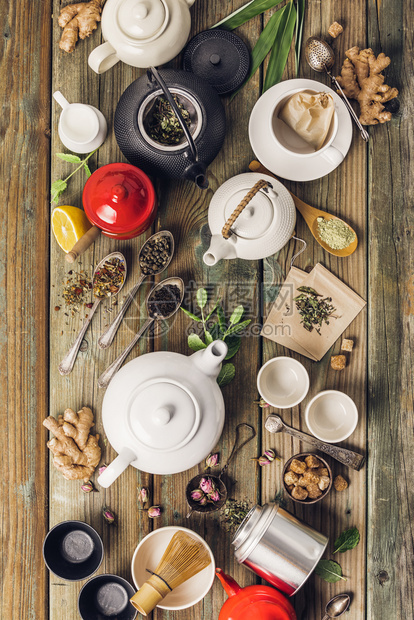 各种茶叶和壶成分干草药绿色黑茶和木制桌底的红茶平铺图片