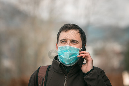 外出时身戴面罩和智能手机的年轻人科罗纳和流感季节图片