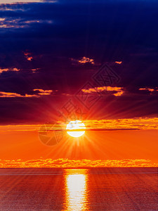 日落时暗云中太阳和海水表面的全景图片