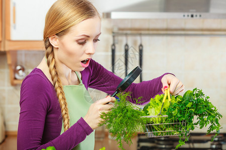 购买健康的饮食品概念厨房里的女人有很多绿色蔬菜她们通过放大镜看购物篮小车女人通过放大镜看蔬菜篮图片