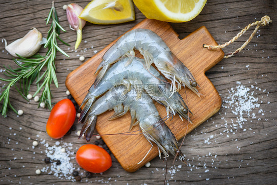木制切板上新鲜虾配有食用海产品生虾的饲料草药和香图片