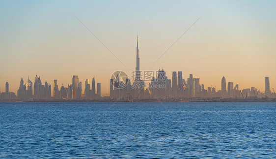 迪拜市下游天线海边有波浪阿拉伯联合酋长国或阿金融区在旅行度假概念上城市天梯大楼和日落空图片