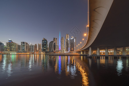 迪拜唐城阿拉伯联合酋长国或阿金融区和城市商业都设有湖泊或河流和桥梁的BurjKhalifa夜里有Skycraper大楼反省图片
