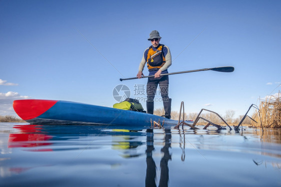 坐在悬浮板上科罗拉多平静湖冬季或初春风景低角动作摄像机视图娱乐健身和培训概念的高级男护板图片